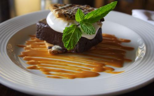 A chocolate torte topped with toasted marshmallow cream, chocolate drizzled graham crackers and a salted dulce de leche sauce